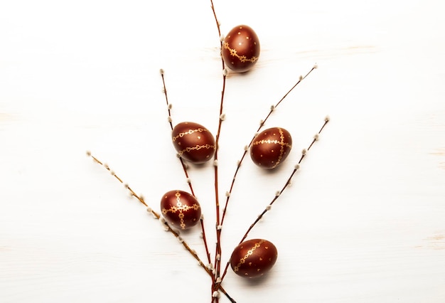 Fond de Pâques blanc avec des oeufs de Pâques brun doré et des branches de saule Vue de dessus avec espace de copie