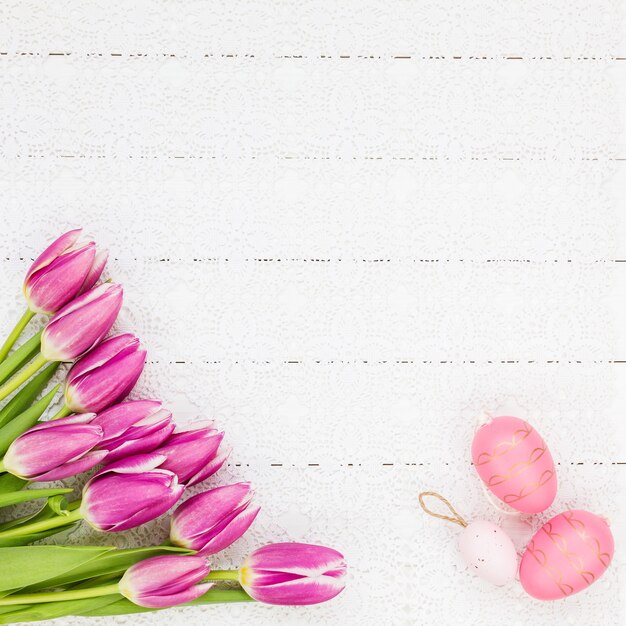 Fond de Pâques. Bouquet de tulipes et oeufs décoratifs sur fond en bois blanc. Vue de dessus