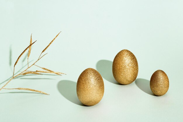 Fond de Pâques avec des oeufs brillants oeufs de couleur dorée brillante et plante sur papier vert