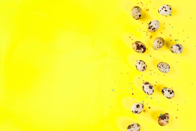 Fond de Pâques avec des oeufs de caille et du sucre saupoudrant sur fond jaune Concept de vacances de printemps