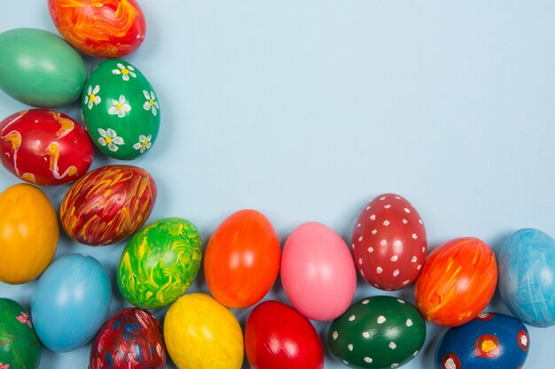 Fond de Pâques avec des oeufs colorés à la main sur un fond bleu clair en bois. Cadre et espace copie.