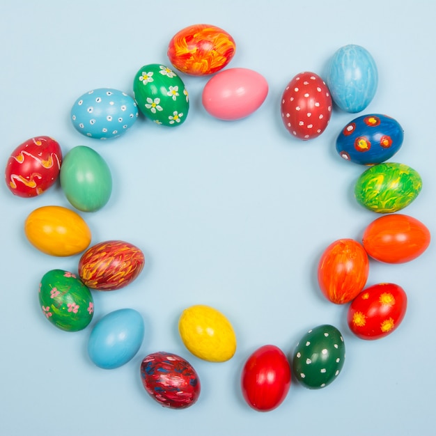 Fond de Pâques avec des oeufs colorés à la main sur un fond bleu clair en bois. Cadre et espace copie.