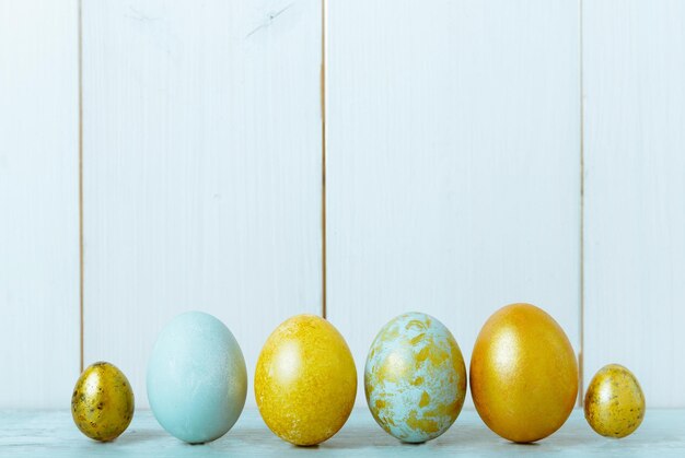 Fond de Pâques avec des oeufs de Pâques bleu et or saule et fleurs de printemps vue de dessus mise à plat avec espace de copie