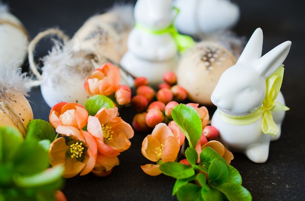 Fond de Pâques avec des oeufs de Pâques décoratifs, des lapins et une branche de printemps en fleurs.