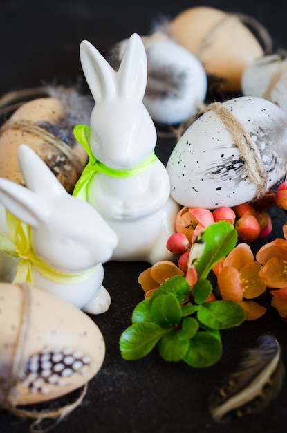 Fond de Pâques avec des oeufs de Pâques décoratifs, des lapins et une branche de printemps en fleurs.