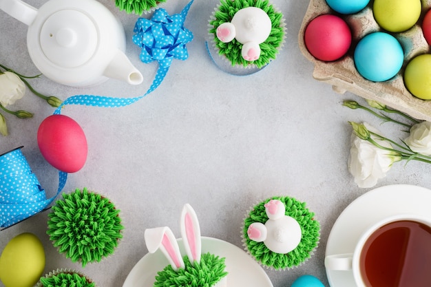 Photo fond de pâques avec des petits gâteaux de lapin, du thé et des œufs peints.