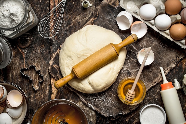 Fond de pâte. Pâte fraîche avec divers ingrédients sur une table en bois.