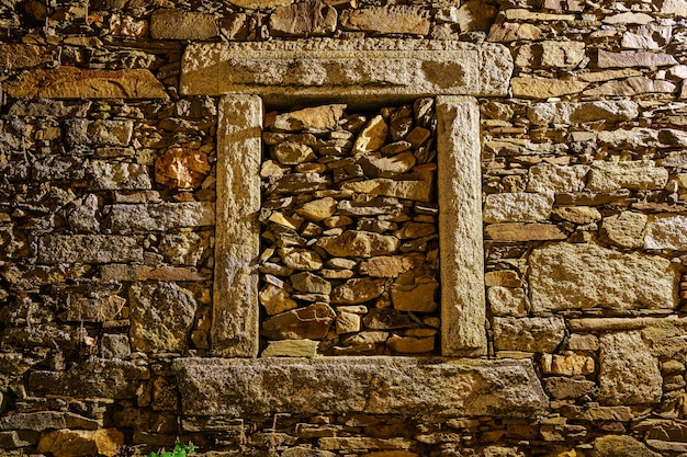 Photo fond en pierre et fenêtre murée la nuit.