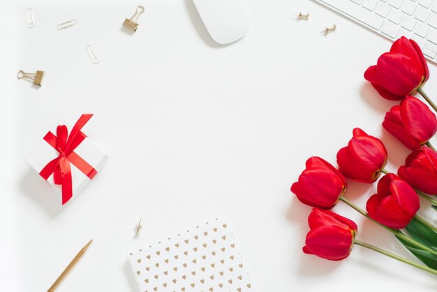 Fond plat laïc de la Saint-Valentin avec clavier d'ordinateur, cadeau, tasse à café et espace de copie blanche vue de dessus de tulipe rouge. Contexte pour un blogueur ou un bureau