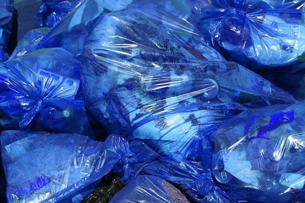 Fond plein cadre de sacs poubelle en plastique bleu avec déchets domestiques génériques