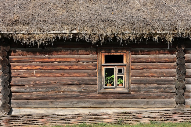 Fond plein cadre et texture de la maison traditionnelle russe en rondins avec toit de paille et une fenêtre sous la lumière directe du soleil