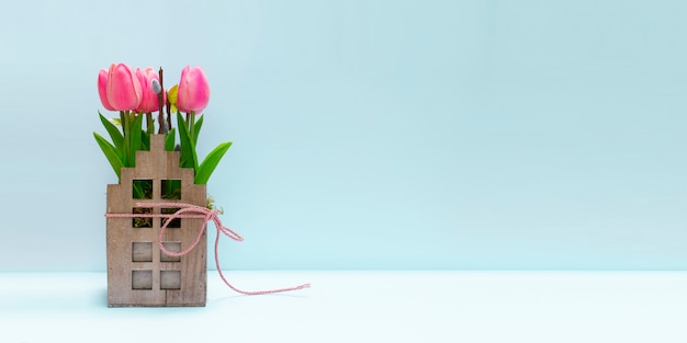 Fond de printemps avec tulipe rose et chat dans un récipient en bois vintage.
