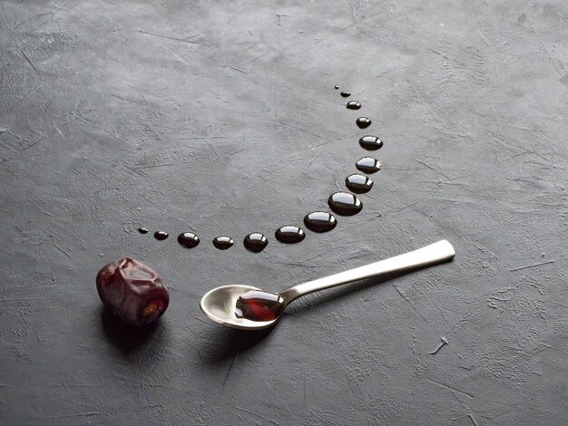 Fond de ramadan noir avec des dates et du sirop de dattes versées en forme de croissant de lune.