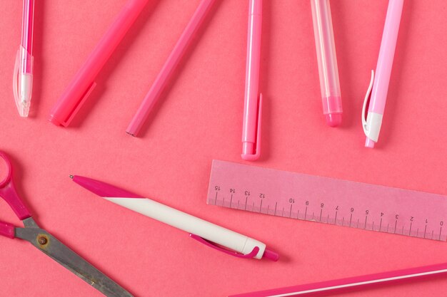 Sur fond rose, accessoires scolaires et stylo, crayons de couleur