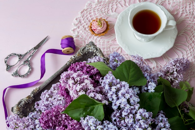 sur un fond rose un bouquet de lilas dans une plaque d&#39;argent ancienne