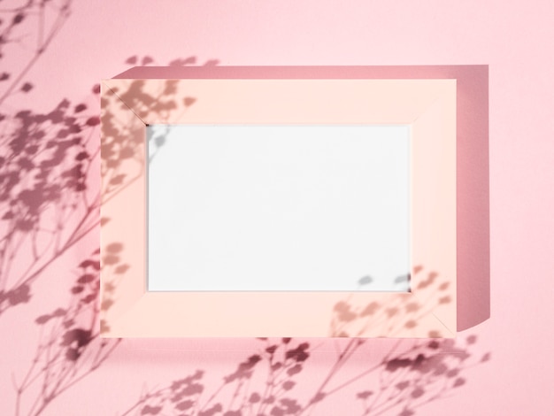 Fond rose avec un cadre photo rose et des ombres de branche