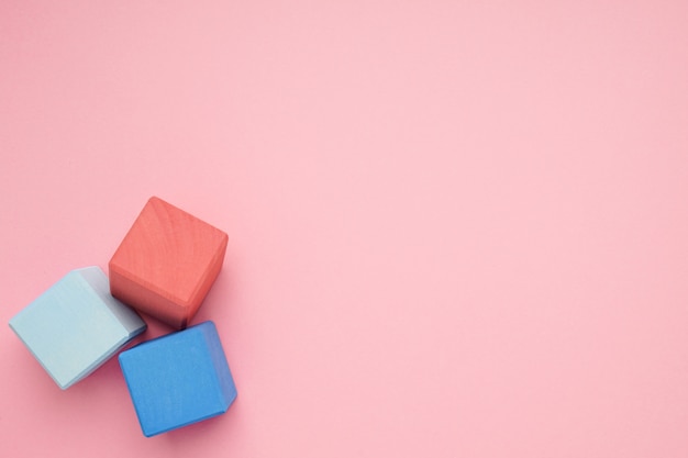 Fond rose avec des cubes en bois colorés. Jouets de créativité. Blocs de construction pour enfants.