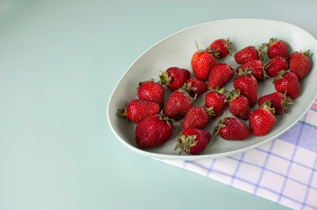 Sur fond rose, il y a une éco-tasse verte avec des fraises fraises bio juteuses rouges Fraises rouge vif en gros plan