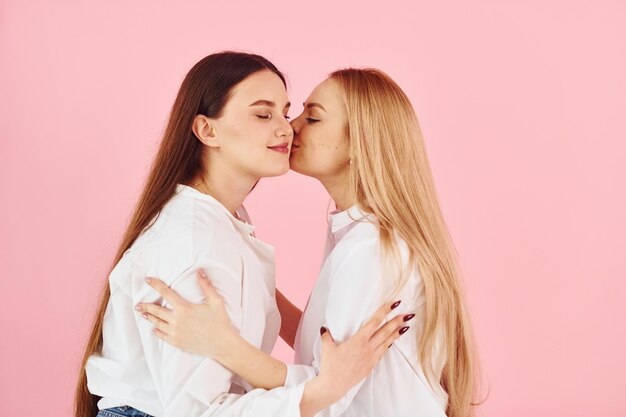 Sur fond rose Jeune mère avec sa fille debout dans le studio