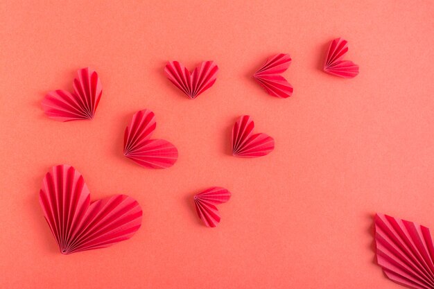 Fond rouge monochrome avec des coeurs en origami volants Saint Valentin
