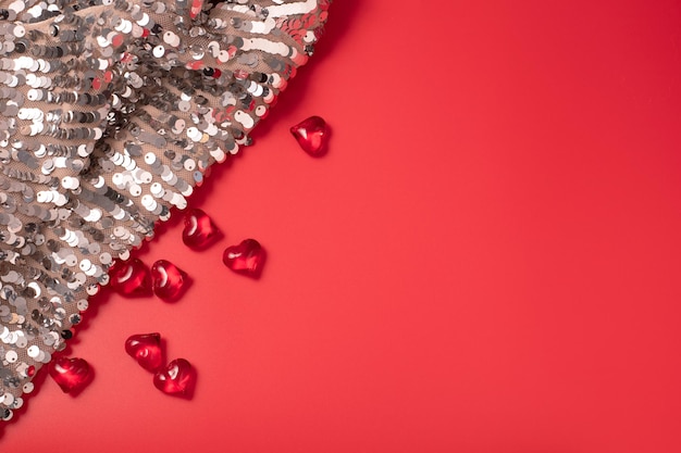 Fond rouge de la Saint-Valentin avec des coeurs et un tissu brillant et scintillant avec des paillettes. Espace libre pour le texte, espace de copie. Carte postale, conception de carte de voeux. Amour, concept de célébration.