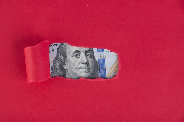 Photo un fond rouge, sous lequel un portrait représenté sur un billet de cent dollars apparaît.