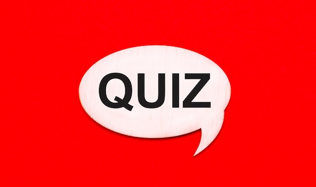 Sur un fond rouge vif, une carte bouclée en bois clair avec une pâte QUIZ