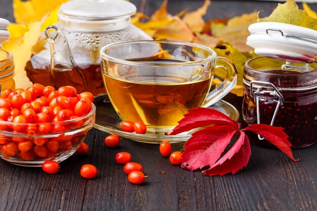 Fond sain. Confiture de fruits sauvages et de framboises, miel et thé sur une table en bois d'automne