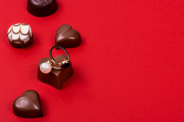 Fond de la Saint-Valentin Chocolats en forme de coeur avec une bague de fiançailles sur fond rouge