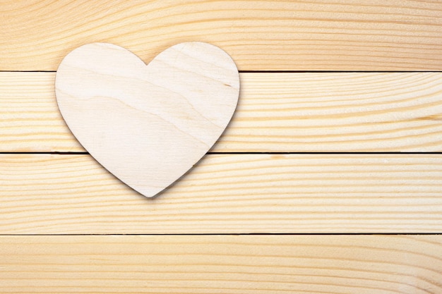 Fond de saint valentin avec un coeur en contreplaqué allongé sur les planches de bois avec un espace de copie