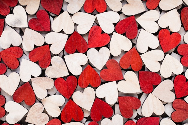 Fond de Saint Valentin avec coeurs rouges fin blanc sur fond en bois.