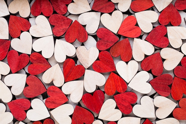 Fond de Saint Valentin avec coeurs rouges fin blanc sur fond en bois.