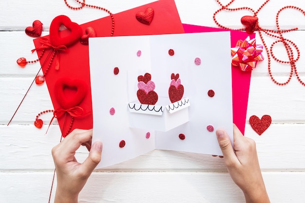 Fond de Saint Valentin. Création de carte de voeux cadeau faite à la main, coupe et colle, papier kraft, feutre et outils de bricolage sur bois blanc. Vue de dessus, mise à plat