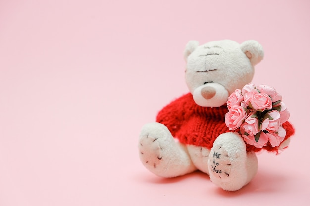 Fond de Saint Valentin. Jouet mignon nounours avec bouquet de fleurs sur fond rose.