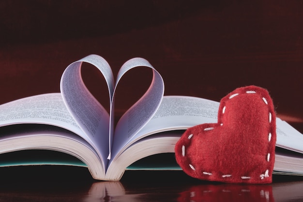 Fond de la Saint-Valentin avec livre ouvert et pages en forme de cœur.