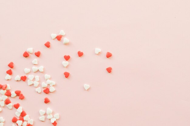 Fond de Saint Valentin avec des petits coeurs rouges et blancs sur fond rose.