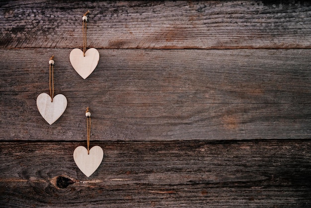 Fond de Saint Valentin planches naturelles brunes dans un style grunge avec trois coeurs décoratifs en bois t...