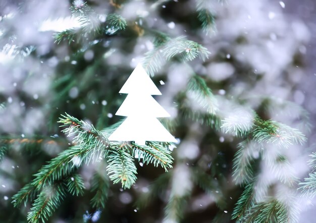 Photo fond de sapin de noël vintage avec jouet en papier fait main dans les chutes de neige.