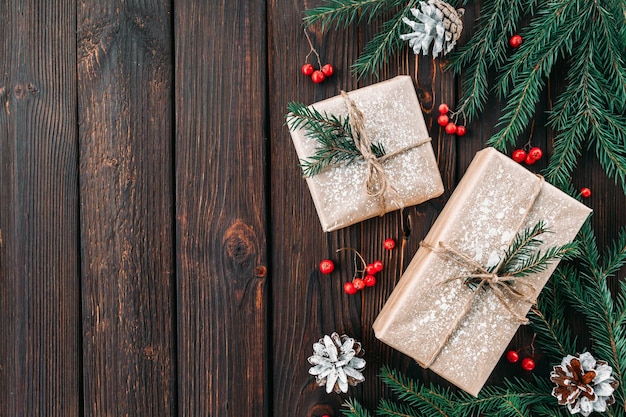 Fond sombre en bois du nouvel an avec des branches d'arbres de Noël avec des cadeaux d'artisanat et des pommes de pin