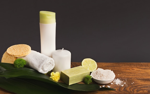 fond de spa. Produits naturels de soin de la peau et d'aromathérapie : bougies, sel de mer, lotion pour le corps et savon d'olive fait main sur fond gris. Salon ou soins à domicile, espace de copie, vue latérale