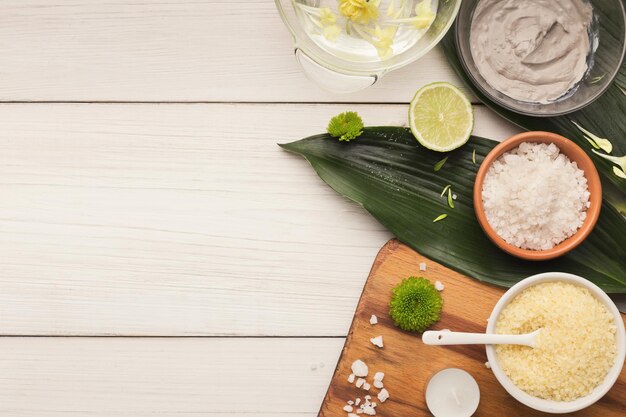 fond de spa. Sel de mer naturel, gommage et masque facial sur des feuilles vertes sur une table blanche. Salon ou soins du corps et de la peau à domicile, espace de copie, vue de dessus