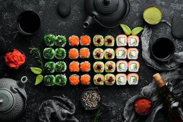 Fond de sushi Assortiment de sushis japonais et de thé sur fond de pierre noire Vue de dessus Espace libre pour votre texte