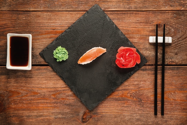 Fond de sushi japonais, nigiri servi sur ardoise noire, sur table rustique en bois, mise à plat. Fruits de mer nationaux sains, délicatesse gastronomique.