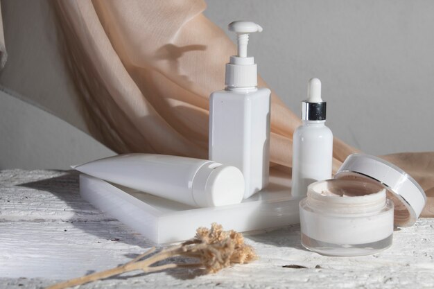 Fond de table en bois blanc avec textile en tissu, produit de crème de lotion de bouteille de maquillage cosmétique avec maquette de soins de santé de mode beauté