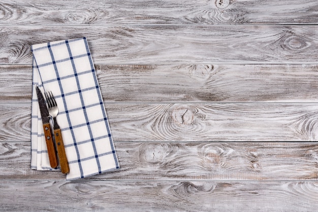 Fond de table en bois vide et fourchette et couteau sur serviette. Concept de dîner, déjeuner ou petit-déjeuner.