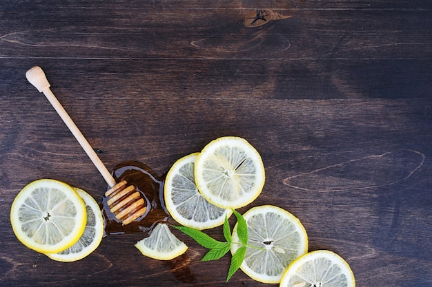 Sur un fond de texture en bois un citron et du miel sur une cuillère