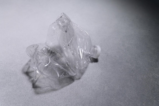 Fond texturé gris une bouteille en plastique froissé se trouve sur la table