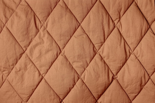 Fond en tissu matelassé. Couverture ou doudoune à texture marron