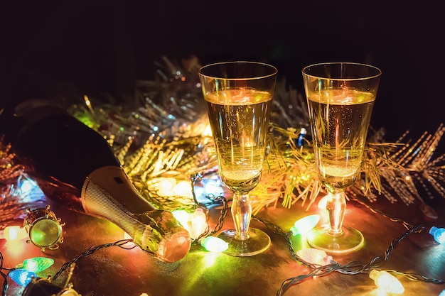 Fond de vacances. Deux verres de champagne et une bouteille sur une table en bois décorée d'accessoires de Noël pour célébrer le nouvel an et Noël. Soirée romantique. La Saint-Valentin