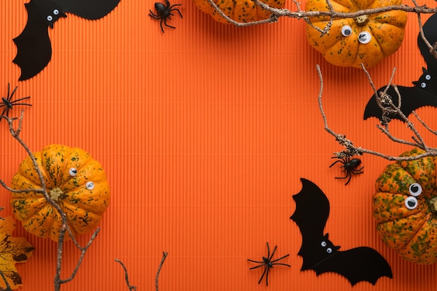 Fond de vacances Halloween Chauve-souris citrouille orange avec des yeux drôles toile d'araignée vieilles feuilles et branches de forêt effrayante sur fond orange Carte d'Halloween heureuse Décoration d'automne Vue de dessus